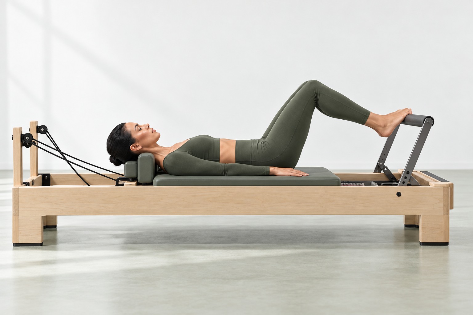 Pilates reformer footwork in a bright white studio