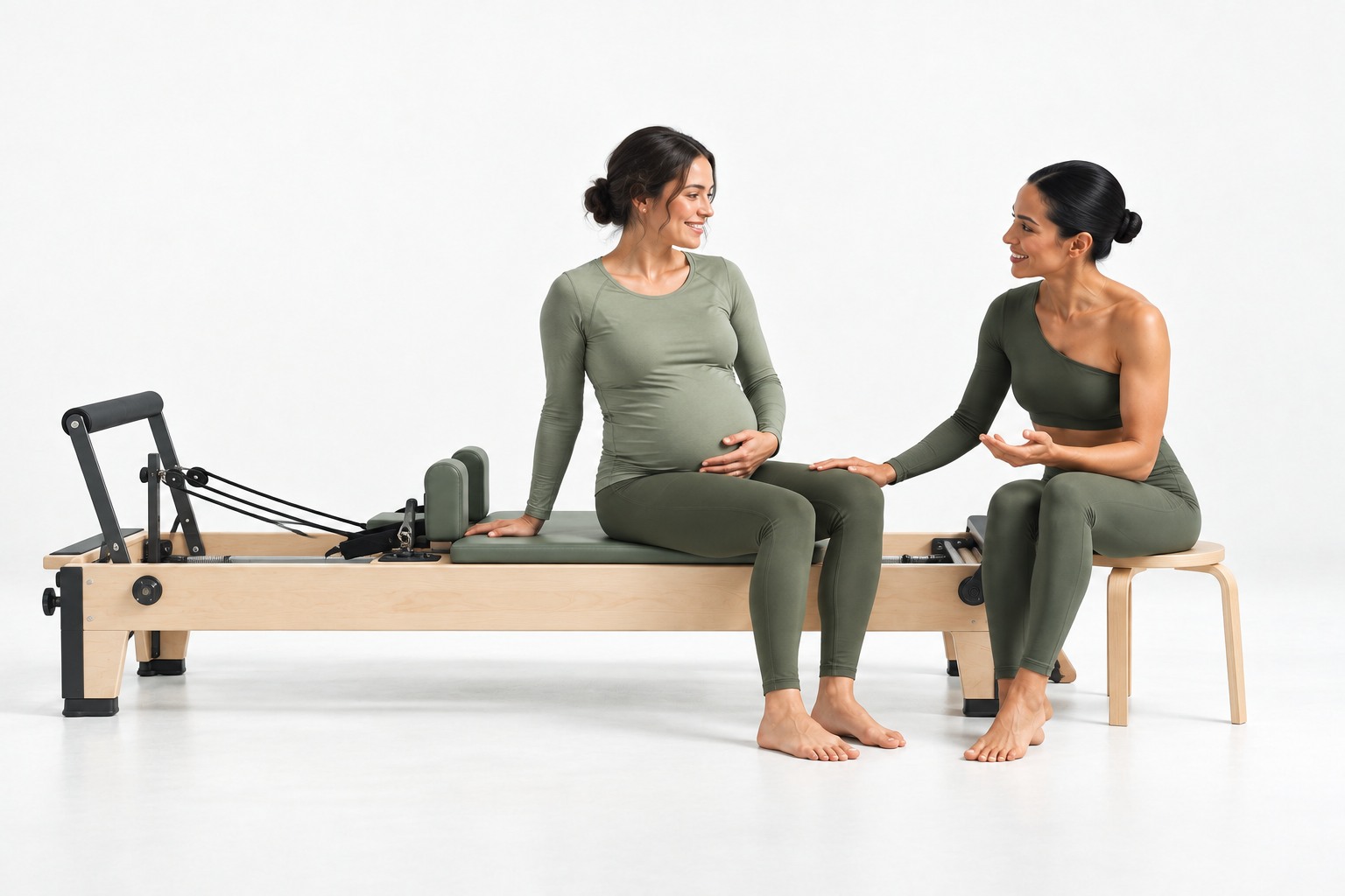 Pregnant client seated comfortably with her Pilates instructor